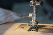 Close up shot of sewing machine steel foot with needle and thread, selective focus