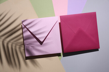 Two envelopes on pastel background with palm leaf shadow. Minimal summer concept. Top view