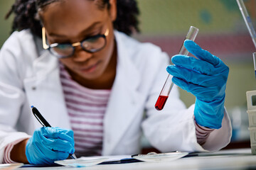 Wall Mural - close up of black medical laboratory scientist analyzing blood test results.