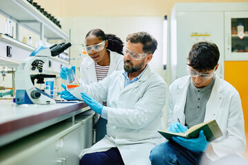 Wall Mural - group of scientists analyzing liquid in beaker while working on medical research in laboratory.