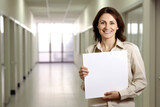 Fototapeta  - Beautiful businesswoman holding a blank sheet of paper in the office