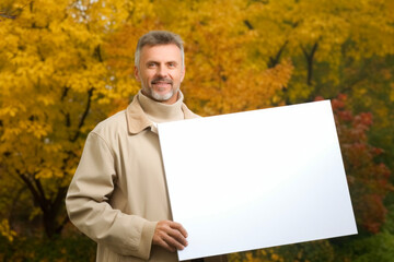 Poster - Mature man holding a white sheet of paper in the autumn park