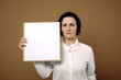 © Robert MEYNER - Businesswoman holding a white board in front of her face on brown background