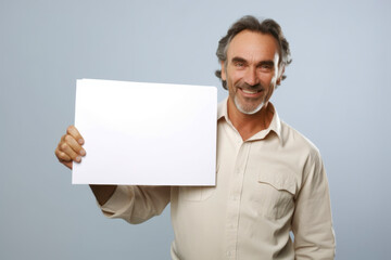 Poster - Portrait of senior man holding blank sheet of paper on grey background