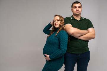 Canvas Print - Image of happy young man standing with his pregnant wife isolated on white wall background. Growing a family, expecting a child, a young family, emotions