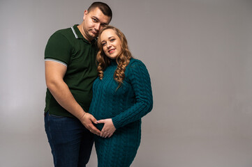 Canvas Print - Image of happy young man standing with his pregnant wife isolated on white wall background. Growing a family, expecting a child, a young family, emotions