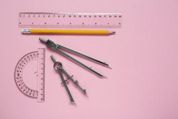 Wall Mural - Different rulers, pencil and compasses on pink background, flat lay. Space for text