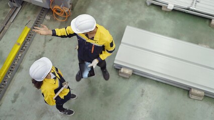 Wall Mural - Top view of industrial engineers men and women wearing safety hard hat standing in plant while working and discuss together at metal manufacturing factory