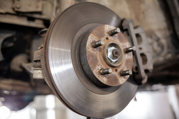Poster - Disc brake of the vehicle for repair, in process of new tire replacement. Car brake repairing in garage.Suspension of car for maintenance brakes and shock absorber systems. Replacement of brake pads.