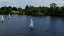 Sailing Dinghies Tacking On Lake Against A Background Of Woodland Trees