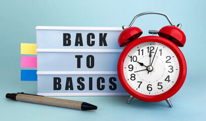 Poster - Text back to basics written on the lightbox with alarm clock and colorfull stickers on blue background