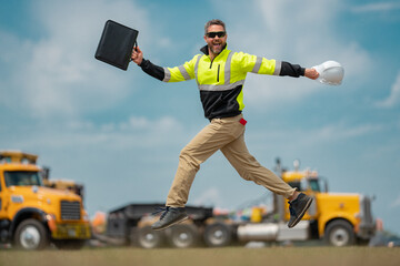 Construction man excited jump with helmet. Builder in helmet outdoor portrait. Worker in hardhat. Construction engineer worker in builder uniform on construction. Excited foreman jump.