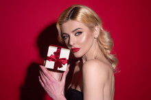 Sexy blonde woman hold gift, isolated on studio background. Holidays celebration concept. Celebrating birthday, receive gift present. Surprised girl with gift. Portrait of attractive woman with gift.
