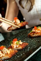 Poster - Vertical shot of chopsticks picking up a gourmet crispy rice salmon sushi roll