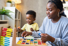 A Cute Little African Child Plays With Colorful Didactic Educational Toys. His Proud Mother Supports Him. Kindergarten Teacher With Child.