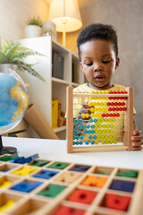 A cute little African child plays with a colorful wooden abacus toy. Educative toys.
