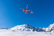 Red Rescue Helicopter Moving In Blue Sky With Blur Propeller In Winter Mountains. Europe Slovakia Poland