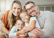 © Jade Maas/peopleimages.com - Parents, portrait and sofa with hug, kids and smile with love, bonding and care in family home together. Father, mother and daughters with happiness, embrace and relax on lounge couch in house