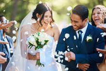 Love, Wedding And Couple Walking With Petals And Guests Throwing In Celebration Of Romance. Happy, Smile And Young Bride With Bouquet And Groom With Crowd Celebrating At The Outdoor Marriage Ceremony