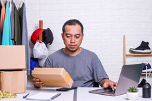 Asian Man Entrepreneur Using Laptop  Prepare Product For Packaging Process, Online Selling. Online Thrifting Store And Business Digital E Commerce Concept. 