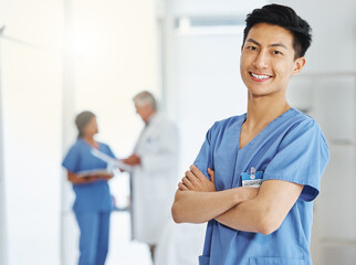 Poster - Portrait, nurse and Asian man with arms crossed in hospital or clinic for healthcare. Face, confidence and happy medical professional, surgeon and doctor with pride for career, job and wellness.