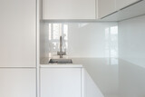 Fototapeta Tulipany - Close-up of the sink and work area in the kitchen with an ultra-thin countertop and glass backsplash