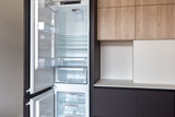 Fototapeta Tulipany - Opened built-in fridge in a kitchen with brown fronts 