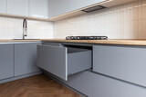 Fototapeta Tulipany - Opened kitchen drawer in a grey white kitchen 