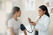 Doctor, blood pressure and patient in a consultation, wellness checkup and appointment with diagnosis, talking and results. Healthcare, woman and medical physician with cuff for hypertension or test