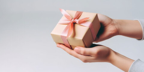 A woman's hands hold a craft gift box with pink satin ribbon bow. Isolated on pastel grey background, with copy space, template for sale, promotion and gift banner. Generative AI photo imitation