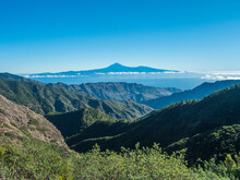 View over lush green landscape of national park Garajonay on La Gomera. In the background the island Tenerife with the Volcano Pico de Teide. Canary Islands, Spain. Blue sky, copy space.