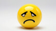 © Barosanu - Funny yellow ball with a sad face on a white background.