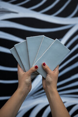 Poster - close up of two female hands holding five sky blue subway tiles against a zebra like background