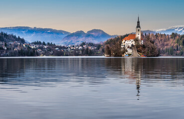 Wall Mural - Panorama shot of Lake Bled island church front and bled village on the left during a clear blue sky, Bled, Slovenia