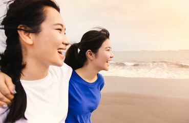 Wall Mural -  Happy girls walking and playing together on tropical beach at summer sunset