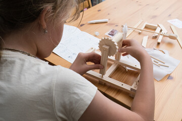 Girl assembling wooden STEM constructor toy.