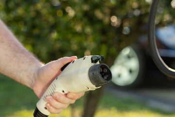 electric car charger, ev, a man charges a car with a type 1 connector at an electric vehicle charging station