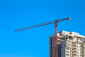 Wall Mural - Construction crane and unfinished building against blue sky