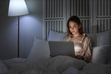 Canvas Print - Young woman using laptop in bedroom at night