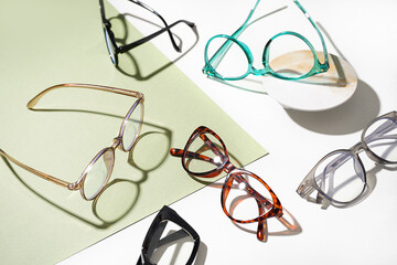 Many different stylish eyeglasses on color background