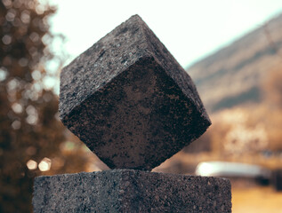 Shallow focus shot of stone cube on horizontal surface on blur background