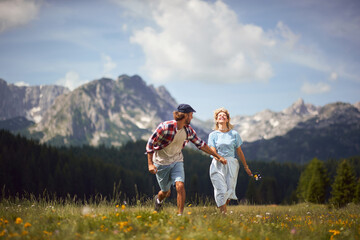 Wall Mural - Beautiful  couple enjoying in nature and running at mountain