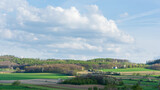 Fototapeta Kuchnia - pola i lasy na pagórkowatym terenie, białe obłoki chmury na błękitnym niebie