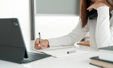 Fototapete - Young woman using digital tablet for online learning at home, writing on her notebook..