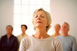 © Anne-Marie Albrecht - Group portrait photography of a woman in her 60s practicing mindfulness sophrology relaxation & stress-reduction wearing a chic cardigan against a minimalist or empty room background