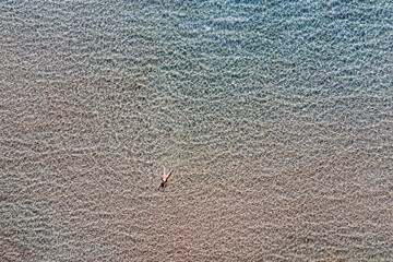 Wall Mural - Woman swims in transparent Aegean sea aerial drone view. Summer leisure Greece Cyclades island.