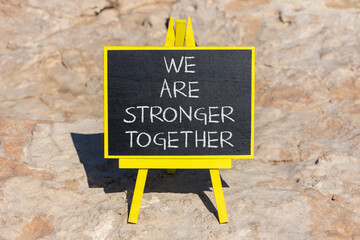 Wall Mural - Stronger together symbol. Concept words We are stronger together on black chalk blackboard on a beautiful stone background. Business, motivational and we are stronger together concept. Copy space.