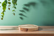 Empty wooden podium log on table with eucalyptus leaves and shadows over green background. Cosmetic mock up for design and product display