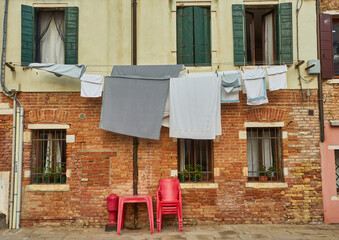 Wall Mural - Typical city corner with ancient colorful buildings Drying clothes on a clothes-line in outdoor at sunny summer day. Venice