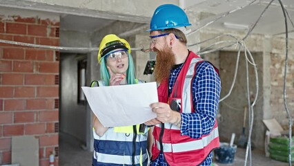 Wall Mural - Man and woman builders reading house project speaking at construction site